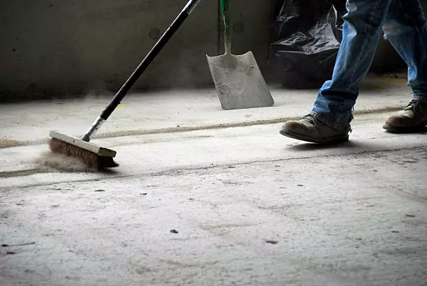 Person deep cleaning a dusty concrete floor.