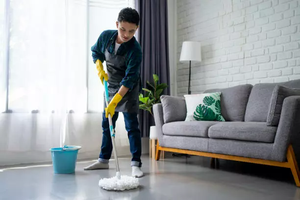 A person from a cleaning company mopping the floor in a living room.
