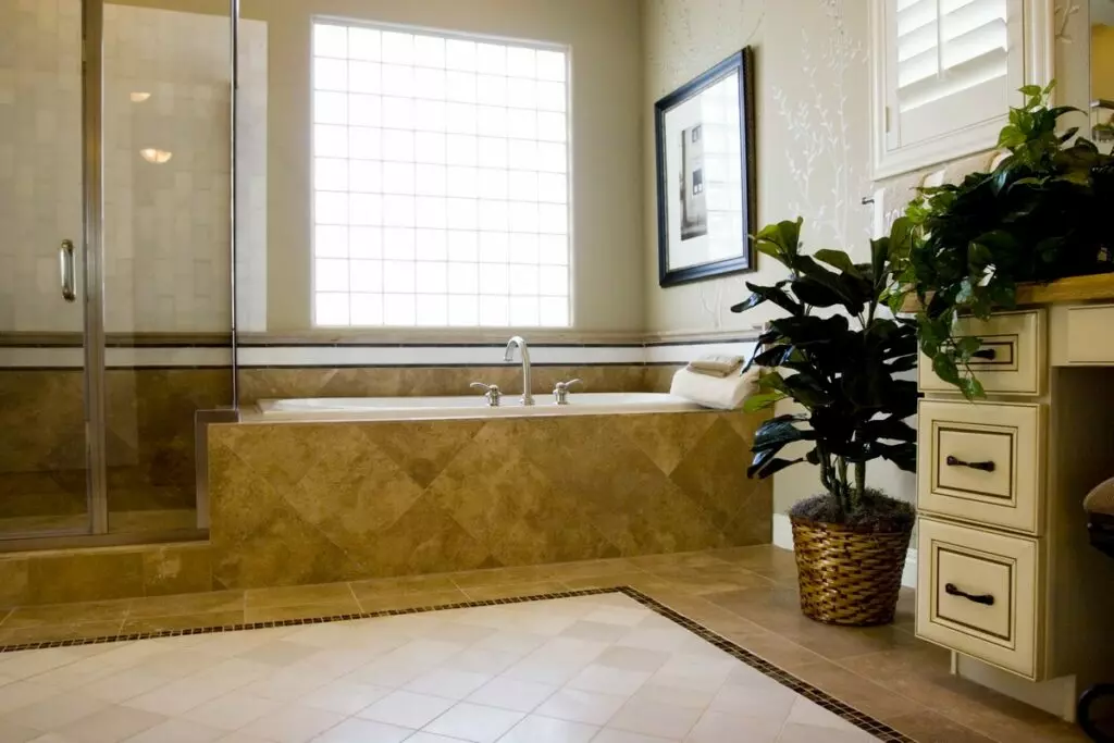Elegant bathroom with a large tub, separate shower, decorative plants, and maid service.